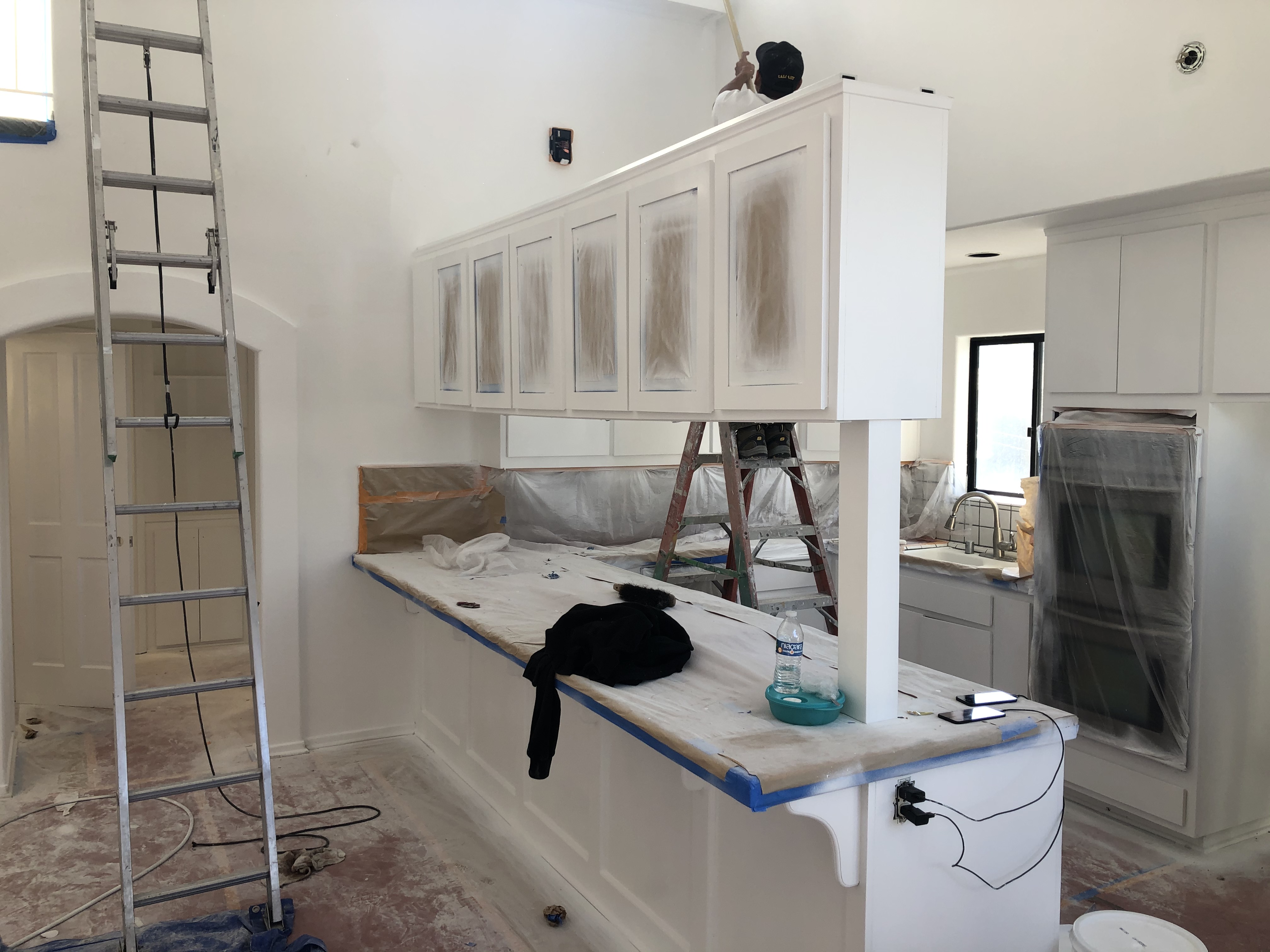 Kitchen painting in progress with protected surfaces