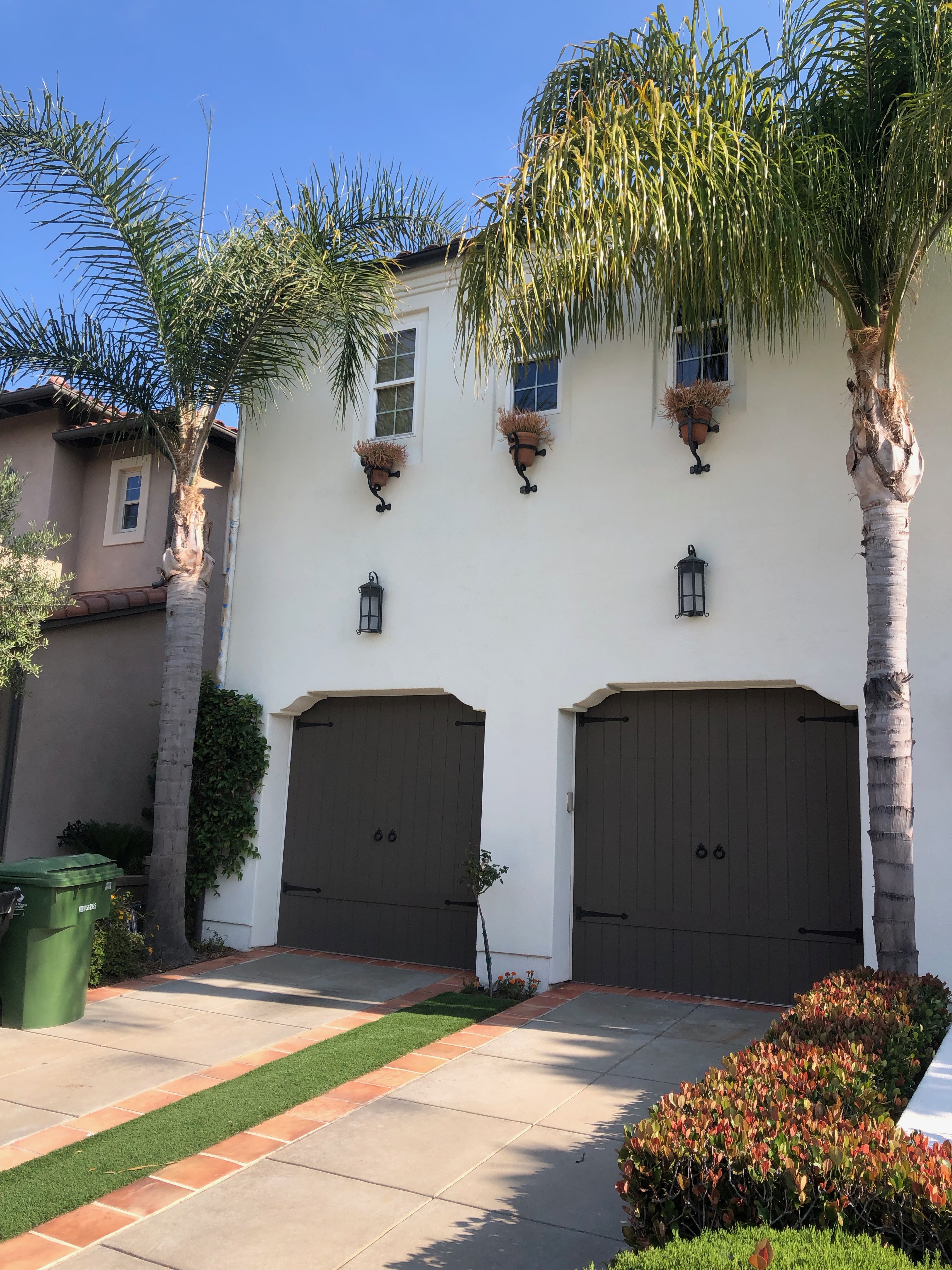 White house exterior with palms and dark garage doors